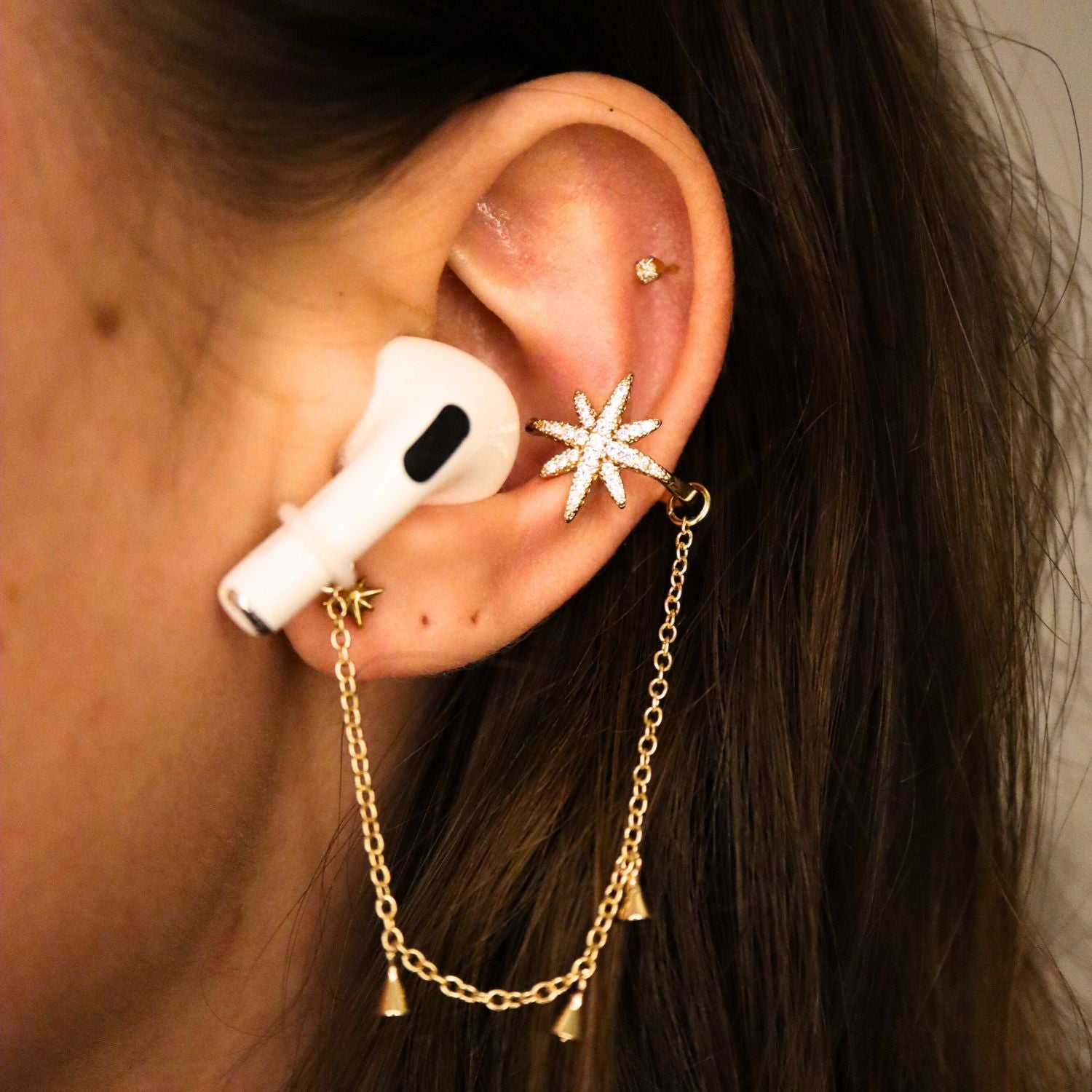 Earcuffs Voor Oordopjes (Ster Kwastjes) Goudkleurig. Op model met Airpods.